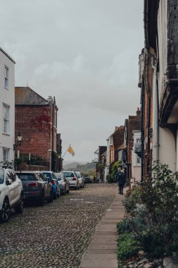 Rye, İngiltere - 10 Ekim 2020: Rye 'da eski teraslı bir evde, doğu Sussex, İngiltere' nin en iyi korunmuş ortaçağ kasabalarından birinde, karşı tarafa park etmiş arabalar, arka planda yürüyen insanlar.