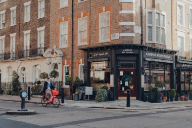 Londra, İngiltere - 5 Aralık 2020: Mayfair 'deki kapalı Almaskoof Irak restoranının önü, Londra' nın batısındaki varlıklı bölge Westminster Borough, bisikletli bir adam, hareket bulanıklığı.