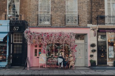 Londra, İngiltere - 5 Aralık 2020: Mayfair 'deki Saint Aymes Kafe' nin Pastel pembeli ön cephesi, Londra 'nın batı ucunda, Westminster Borough' da zengin bir bölge, kadınlar dışarıda bir masada..