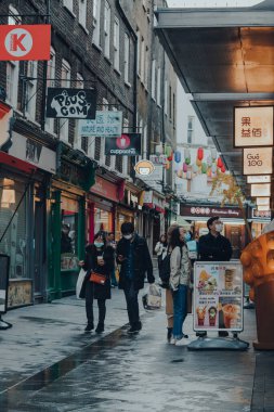 London, UK - November 19, 2020: People wearing face masks in Chinatown area in London. Chinatown is home to a large East Asian community and is famous for its eateries and events. Selective focus.