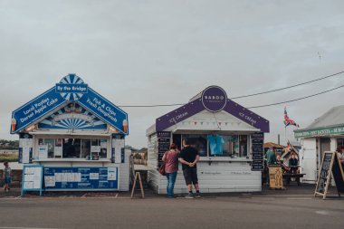 Eype Beach, UK - July 25, 2020: People buying take away food from food stalls West Bay, a small harbour settlement and resort on the English Channel coast in Dorset.