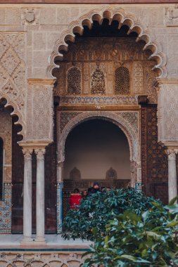 Seville, İspanya - 19 Ocak 2020: Sevilla 'daki Patio de Maidens avlusuna kemerli giriş, Hristiyan kral Kastilyalı Peter için yapılmış bir kraliyet sarayı, arka planda turist yürüyüşü.