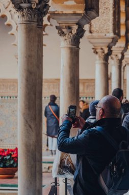 Seville, İspanya - 19 Ocak 2020: Kastilya Kralı Peter için yapılmış bir kraliyet sarayı olan Sevilla 'nın içindeki Patio de Maidens avlusunun fotoğraflarını çeken adam..