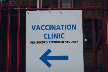Londra, İngiltere 'de bir caddedeki Aşı Kliniği' nde önceden randevu almak için yön tabelası..