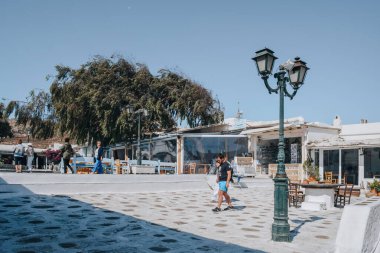 Ana Mera, Yunanistan - 24 Eylül 2019: Güneşli bir günde, Mykonos Adası 'ndaki bir kasaba olan Ana Mera' daki kasaba meydanında yürüyen insanlar.