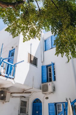 Mykonos Town, Yunanistan - 24 Eylül 2019: Adaların iyi korunmuş liman ve başkenti Hora 'da (Mykonos Town) mavi renklerle boyanmış geleneksel evlerin düşük açılı görünümü.