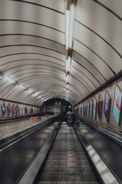 Londra, İngiltere - 03 Eylül 2021: Moorgate Londra metro istasyonunda aşağı yürüyen merdiven, dünyanın en eski yeraltı demiryolu, seçici odaklı.