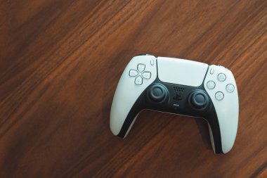 Londra, İngiltere - 25 Mayıs 2021: Tahta bir masanın üzerinde Playstation 5 (PS5) denetleyici. Playstation 5, Sony 'nin Kasım 2020' de PlayStation 4 'ün ardılı olarak piyasaya sürdüğü son video oyunu konsoludur..
