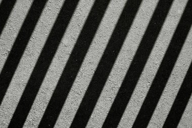 Asfalt yol yüzeyinde siyah beyaz gölgeler var..
