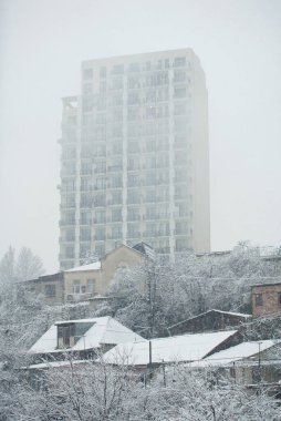 Eski evlerle çevrili çok katlı bir bina. Kışın sisli sabahı.