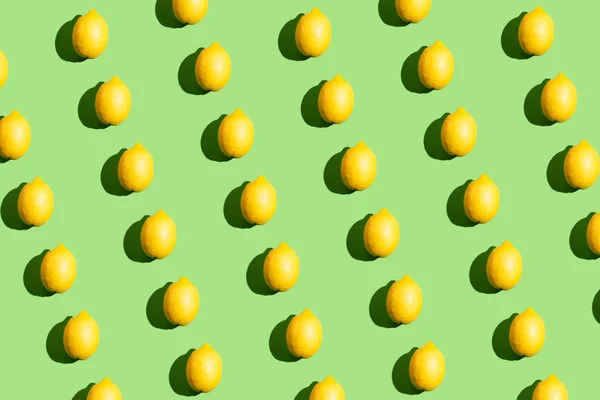 緑の背景に硬質の影を持つレモンで作られたカラフルなポップアートスタイルの繰り返しパターン — ストック写真