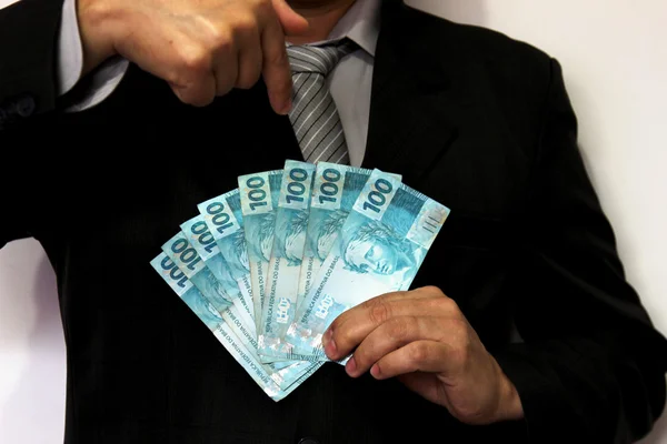 Man in suit holding money notes and pointing