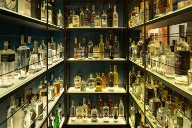 Kyiv, Ukrayna - 20 Ekim 2025: Bir bar deposunda votka, viski ve diğer ruhlarla dolu iyi düzenlenmiş içki rafları, sergilenmek için yumuşak arka ışıklandırmayla aydınlatılmış.