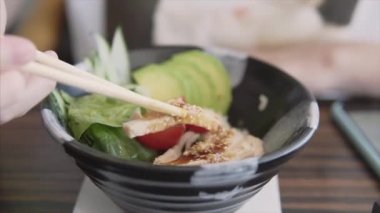 Kadın, avokado, domates, pirinç, ıspanak ve tavuklu bir kase yer.. 