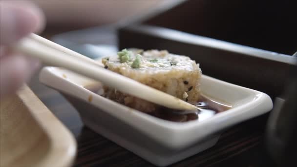 Asiatisk restaurang besökare doppade sushi roll i soja sås och äter det. — Stockvideo