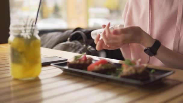 Weibliche Hände tragen vor dem Essen ein antiseptisches Gel auf, ein Desinfektionsmittel für hygienische Zwecke. — Stockvideo