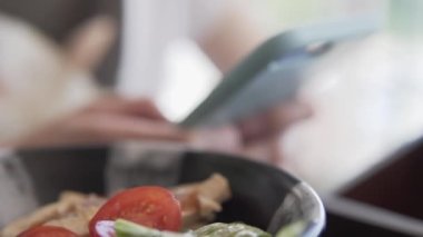 Kadın lokantada yemek yerken akıllı telefon kullanıyor..