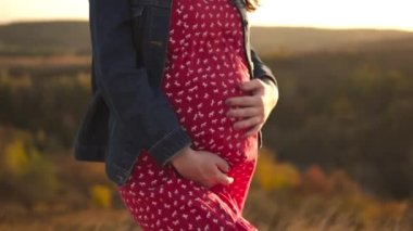 Hamileliğin kutlu olsun, hamile anne gün batımında karnına dokunur.. 