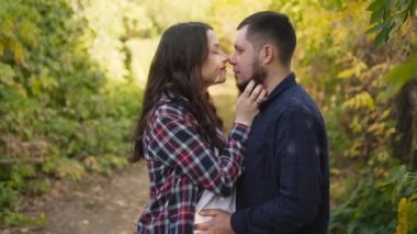 Genç bir çift, gelecekteki ebeveynler doğada sarılıyorlar, adam nazikçe kızların burnunu ısırıyor..