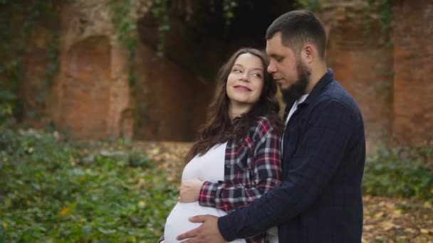 Moeder en vader, ouders in de toekomst knuffelen en kijken naar een zwangere buik. — Stockvideo