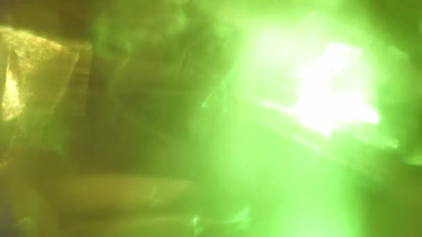 Bunte Lichtstrahlen durchdringen das Glas. Grüne und gelbe Farben. — Stockvideo