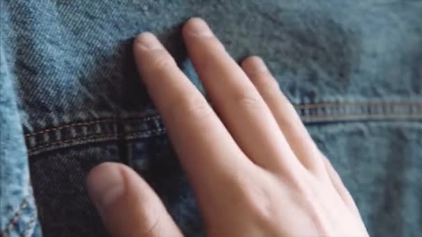 Muž ruka se dotkne modrého denim, kontrola jeho kvality před nákupem v prodejně oděvů. — Stock video