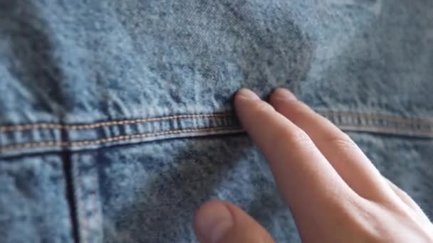 Hand of a caucasian person touches blue denim jeans jacket. — Stock Video