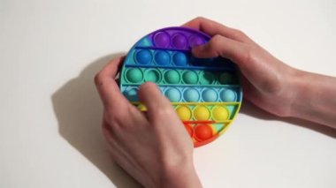 Kadın, popüler renkli bir oyuncağın sivilcelerine bastırıyor ve onu patlatıyor. Silikon anti-stres oyuncağı..