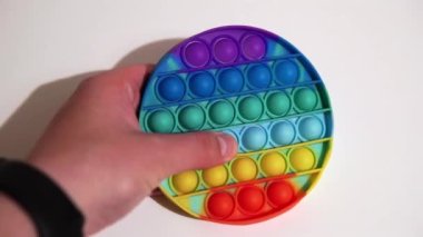 Adam popüler renkli bir oyuncağın sivilcelerine bastırıyor ve patlatıyor..