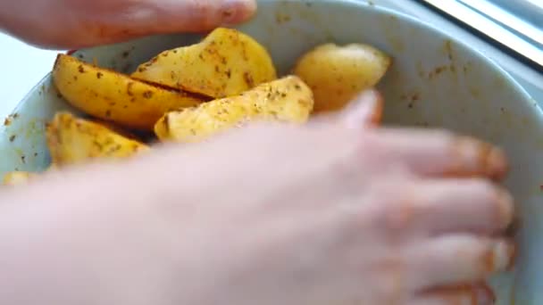 Les mains des femmes mélangent des tranches de pommes de terre avec de l'huile et des épices et des herbes dans un bol profond. — Video