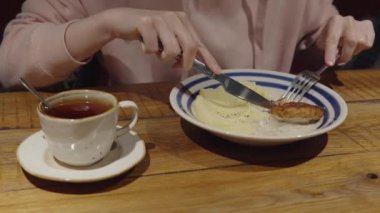 Pembe kapüşonlu bir kadın restoranda patates püresi ve tavuk pirzolası yiyor..