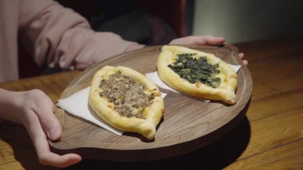 La chica muestra delicioso khachapuri georgiano con queso, espinacas y champiñones. — Vídeos de Stock