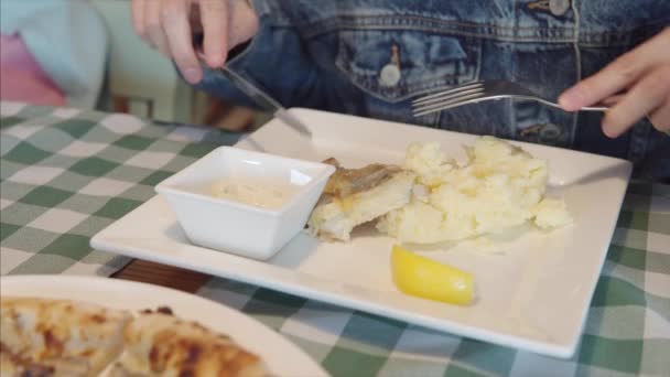 Dziewczyna w dżinsowej kurtce wylewa sok z cytryny na rybę.. — Wideo stockowe