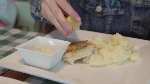 A girl in a denim jacket pours lemon juice on the fish. — Stok Video