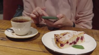 Pembe kapüşonlu bir kız haberlere bakıyor, akıllı telefonundaki fotoğraflar, kafede oturan bir randevu uygulaması kullanıyor..