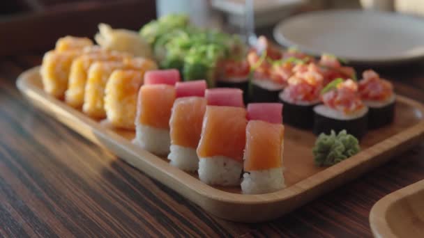 Conjunto de vários rolos de sushi composto por algas, arroz, noria, salmão, atum e queijo Filadélfia. — Vídeo de Stock