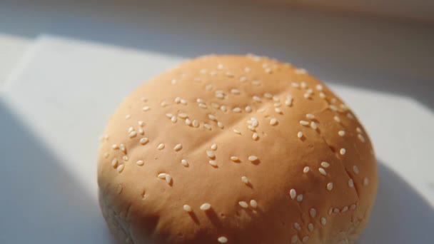 Un primo piano di un panino fresco e profumato cosparso di sesamo giace su una tavola da cucina bianca. — Video Stock