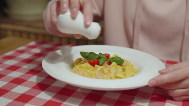 Espolvorea la mano de las mujeres con pimienta molida pasta de calabaza italiana con camarones, albahaca, tomates y salsa. — Vídeos de Stock