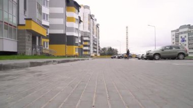 Tasmalı küçük bir okul çocuğu uzun kulaklı bir köpek olan Cavalier King Charles Spaniel 'i gezdiriyor. Soğuk bulutlu bir günde çok katlı binaların arka planında yürümek. Evcil hayvanlar