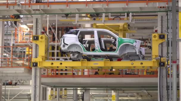 Carrosserie op transportband. Moderne assemblage van auto 's in de fabriek. Het geautomatiseerde bouwproces. De groep robots verricht gezamenlijk werk aan het monteren en lassen van de carrosserie van een moderne auto 4k — Stockvideo