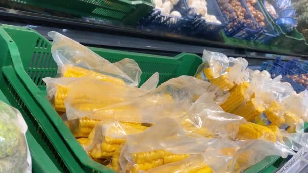 Yellow large corn in a vacuum package on the supermarket counter in a green basket in a grocery. Customer choosing fresh farm vegetables. Veggy healthy lifestyle. Organic food. Season sal 4k — 비디오