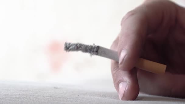 Zblízka zapálená a hořící cigareta kouřem. Kouřící cigareta během obláčku. Ruka člověka se špatnými návyky drží nebezpečnou cigaretu. Kouření kvůli požáru. Deprese posedlosti 4k — Stock video