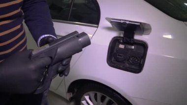 Siyah lastik eldivenli bir atıcı yüksek gerilimli elektrikli aracın kablosunu arabaları şarj etmek için metal lensleri olan bir yere yerleştirir. Eko arabanın şarj olduğu kapak. Çevre enerjisi 4K