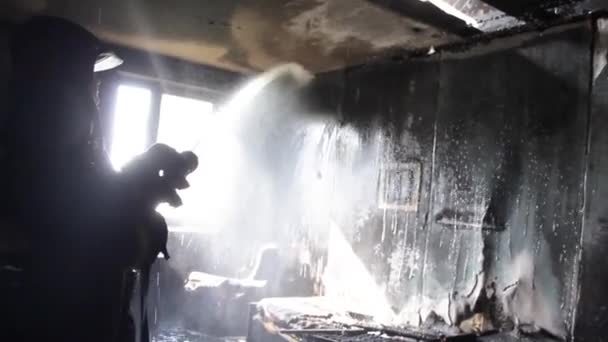 Пожарный выбрасывает горящую мебель в комнату в квартире у Огненной Костры. Тушение лесного пожара. Костер. Много дыма, пар от огня потушен. Пожарный распыляет воду и пену из шланга — стоковое видео