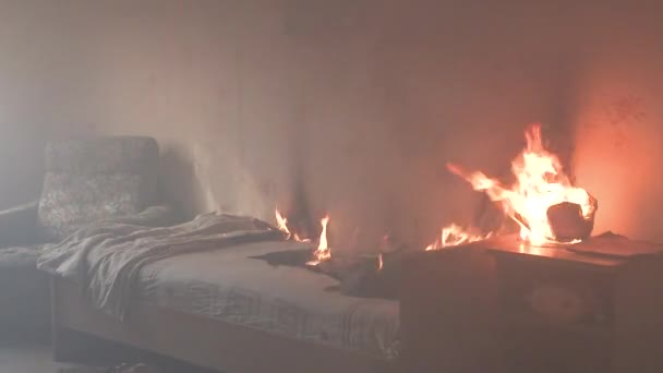 El dormitorio está en llamas con mucho humo. La cama, la mesita de noche, la tetera de plástico, el papel pintado y las estanterías están en llamas en una casa residencial. Fotografía cinematográfica de las secuelas de un incendio de dos alarmas 4k — Vídeo de stock