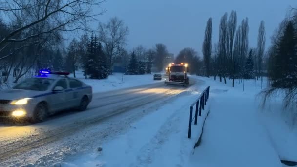 Minsk, Biélorussie - 02.09.2021 : Unités municipales avec soufflets Enlever les chutes de neige. Une colonne de balayeuses avec des feux clignotants éclairent les rues enneigées de la ville, les arbres sont couverts de neige. Météo scandinave 4k — Video