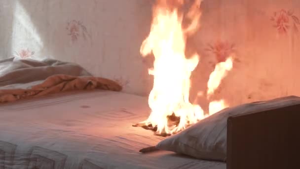 El dormitorio está en llamas con mucho humo. La cama, la mesita de noche, la tetera de plástico, el papel pintado y las estanterías están en llamas en una casa residencial. Fotografía cinematográfica de las secuelas de un incendio de dos alarmas 4k — Vídeo de stock