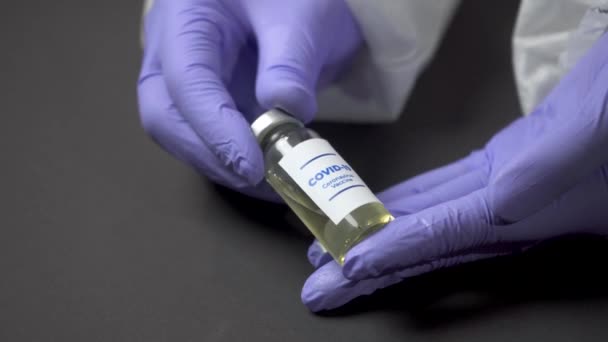 Руки в сині рукавички тримають ліки. Коронавірусна вакцина виявлена в медичній лабораторії. Вакцинація для концепції вірусу COVID-19. Ампула з вакциною. Очищення і розчин коронавірусної пандемії 4k — стокове відео