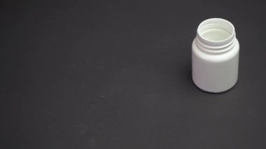 Kapalı kadının eli, beyaz haplarla dolu reçeteli ilaç şişesinden dökülüp etrafa saçılmış. Beyaz haplar siyah sağlık masasına dökülüyor. Sağlık ve ilaç kavramı 4k