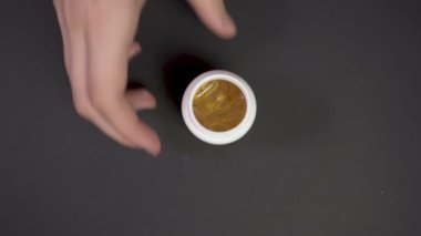 Kapalı kadının eli, içinde sarı haplar olan reçeteli ilaç şişesinden düşüp etrafa saçılıyor. Sarı haplar siyah sağlık masasına dökülüyor. Sağlık ve ilaç kavramı 4k